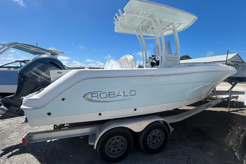 The Image of 2021 Robalo R222 Explorer boat on trailer, featuring Yamaha outboard motor, under clear blue sky. - 0