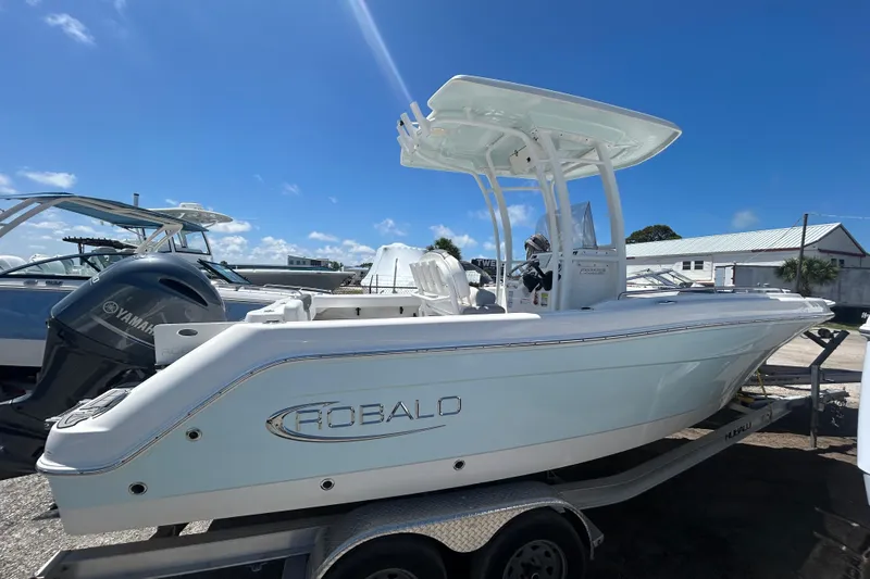 Slide: The Image of 2021 Robalo R222 Explorer boat on trailer, featuring Yamaha outboard motor, under clear blue sky. - 2