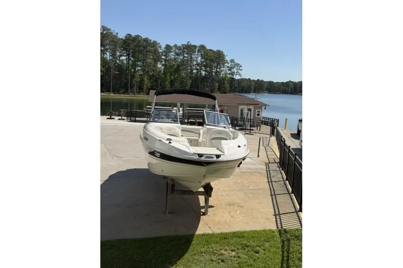 Slide: The Image of 2012 Stingray 235 LR boat on a dock by a lake with trees in the background. - 4