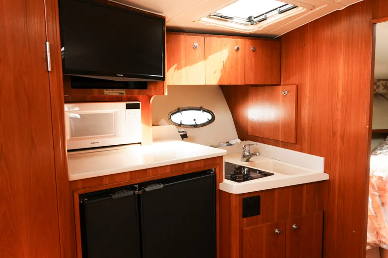 Slide: The Image of 1999 Tiara Yachts 3500 Open interior kitchen with microwave, sink, and TV. - 11