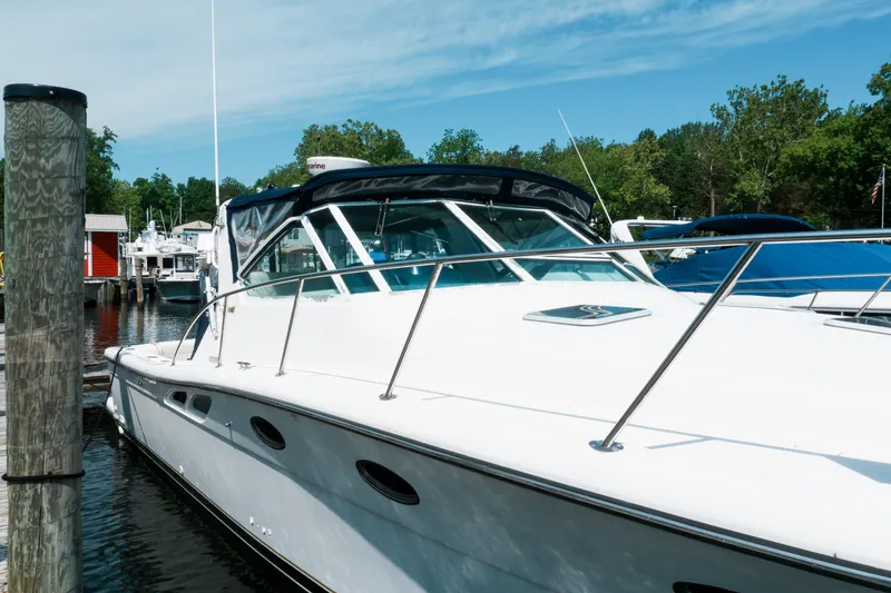 Slide: The Image of 1999 Tiara Yachts 3500 Open docked at a marina, surrounded by trees and boats. - 3