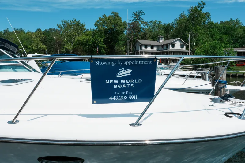 Slide: The Image of 1999 Tiara Yachts 3500 Open with New World Boats sign, docked near trees. - 4