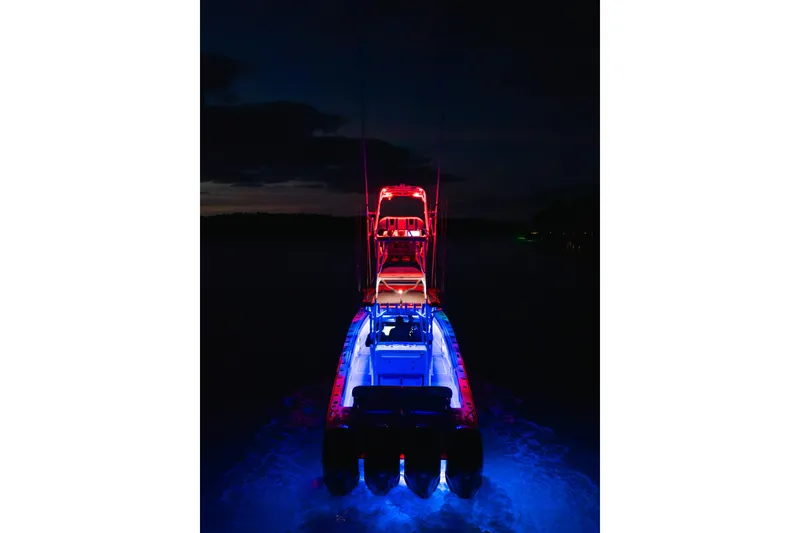 Slide: The Image of Nor-Tech 392 Super Fish 2022 boat illuminated with vibrant red and blue lights at night. - 54