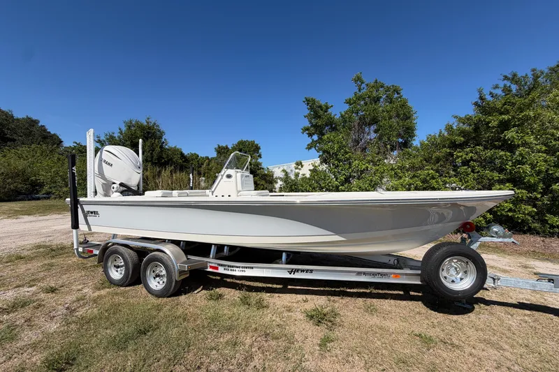 The Image of 2026 Hewes Redfisher 21 boat on trailer, parked outdoors under clear blue sky. - 1