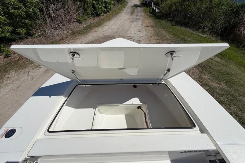 Slide: The Image of 2026 Hewes Redfisher 21 boat storage compartment open, showing spacious interior on a dirt path. - 13