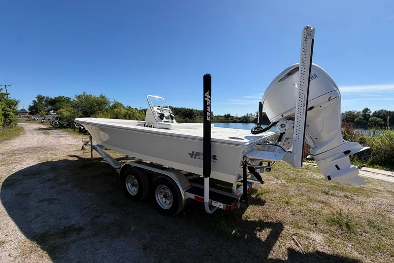 Slide: The Image of 2026 Hewes Redfisher 21 boat on trailer by a lakeside under clear blue sky. - 4
