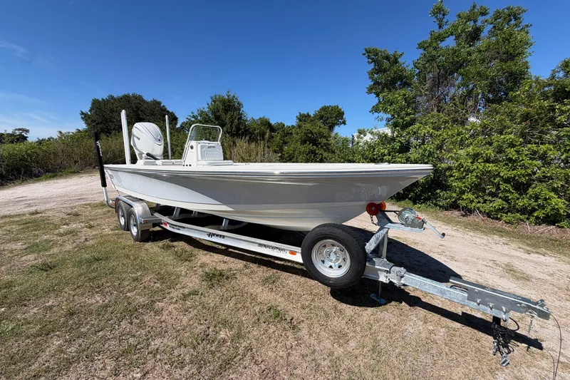 Slide: The Image of 2026 Hewes Redfisher 21 boat on trailer, parked outdoors with trees in background. - 5
