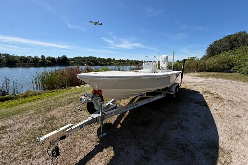 Slide: The Image of 2026 Hewes Redfisher 21 boat on trailer by a lake, airplane in sky. - 7