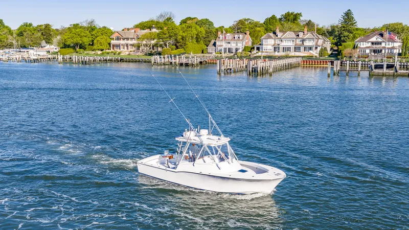 Slide: The Image of 2005 L&H Walkaround boat on calm water near coastal homes. - 19