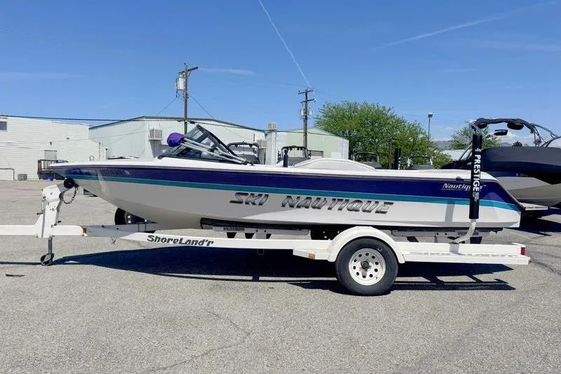 The Image of 1995 Correct Craft Ski Nautique boat on trailer in parking lot. - 1