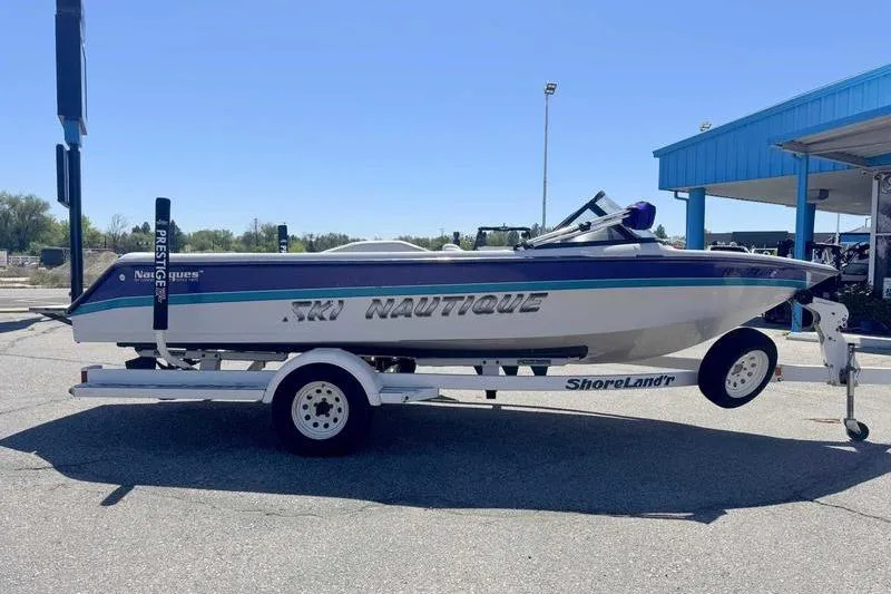 Slide: The Image of 1995 Correct Craft Ski Nautique boat on trailer, parked outdoors under clear blue sky. - 5