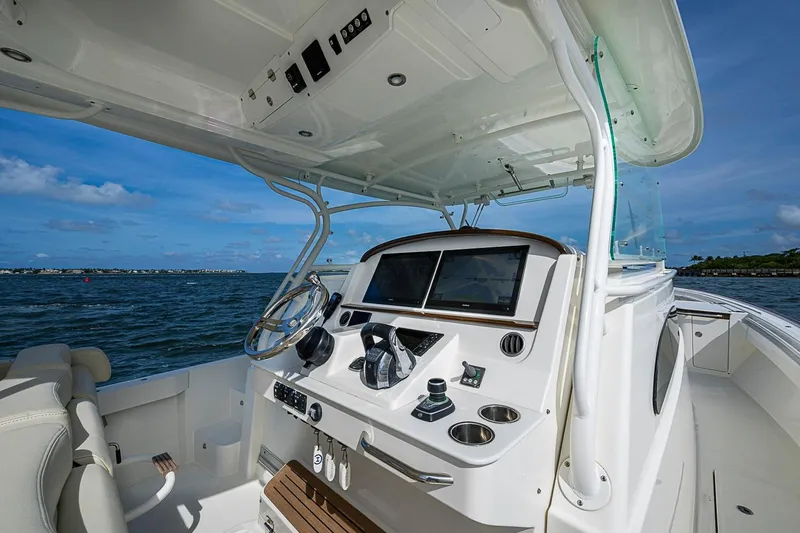 Slide: The Image of 2019 Hinckley Sport Boat 40 C helm with dual screens, steering wheel, and ocean view. - 12