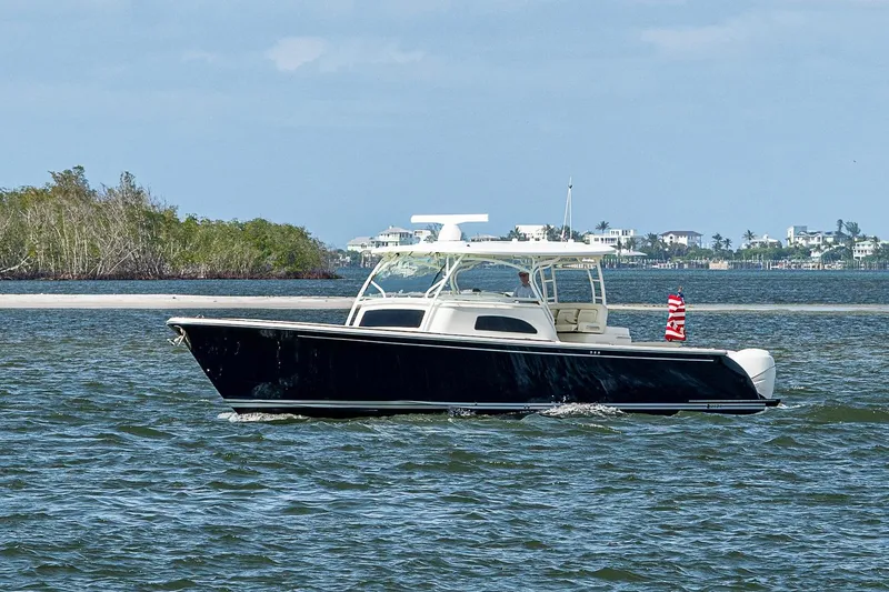 Slide: The Image of 2019 Hinckley Sport Boat 40 C cruising on open water near a coastal area. - 3