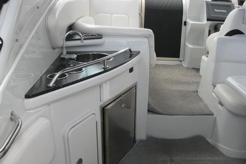 Slide: The Image of Interior of 2010 Crownline 330 CR boat featuring a sleek kitchenette and seating area. - 14