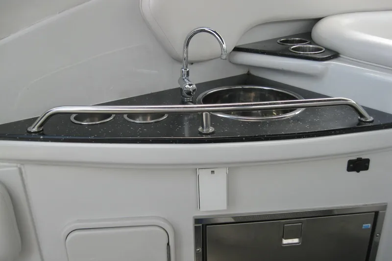 Slide: The Image of 2010 Crownline 330 CR boat kitchenette with sink and cup holders. - 17