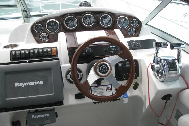Slide: The Image of 2010 Crownline 330 CR boat dashboard with steering wheel and Raymarine navigation system. - 21