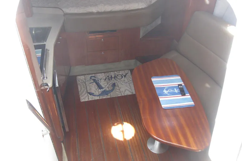 Slide: The Image of Interior of 2010 Crownline 330 CR boat with wooden table and seating area. - 27