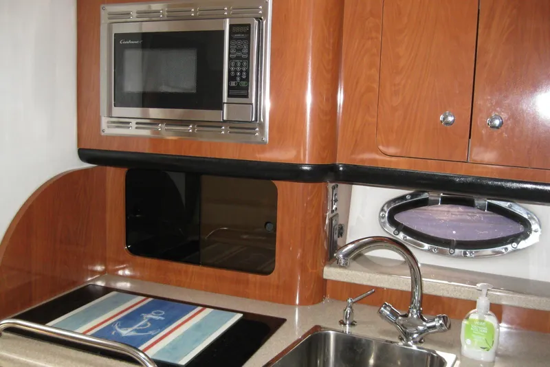 Slide: The Image of 2010 Crownline 330 CR yacht kitchen with microwave, sink, and porthole window. - 30