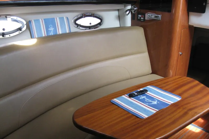 Slide: The Image of Interior of 2010 Crownline 330 CR boat with wooden table and beige seating. - 31