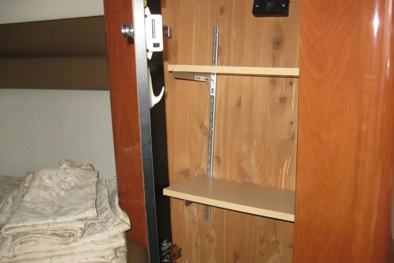 Slide: The Image of Interior of 2010 Crownline 330 CR showing wooden cabinet with shelves and bedding. - 32