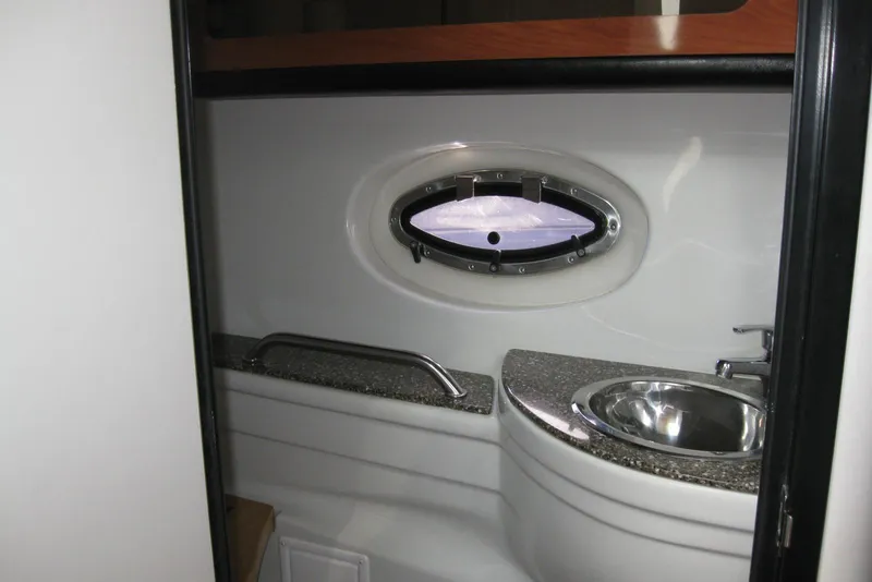 Slide: The Image of 2010 Crownline 330 CR boat bathroom with oval window and stainless steel sink. - 38