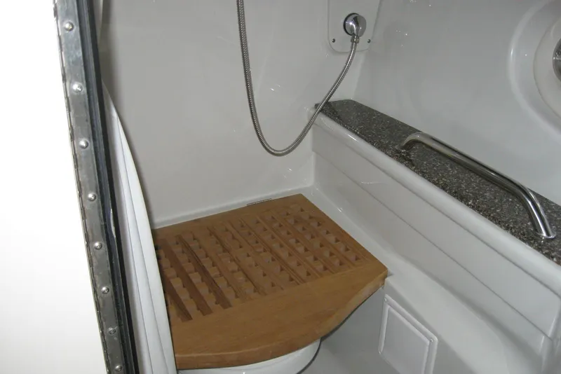 Slide: The Image of Interior of 2010 Crownline 330 CR boat shower with wooden seat and metal handle. - 39
