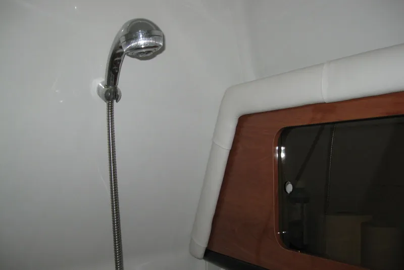 Slide: The Image of Shower area in 2010 Crownline 330 CR boat with chrome fixtures and wooden accents. - 40