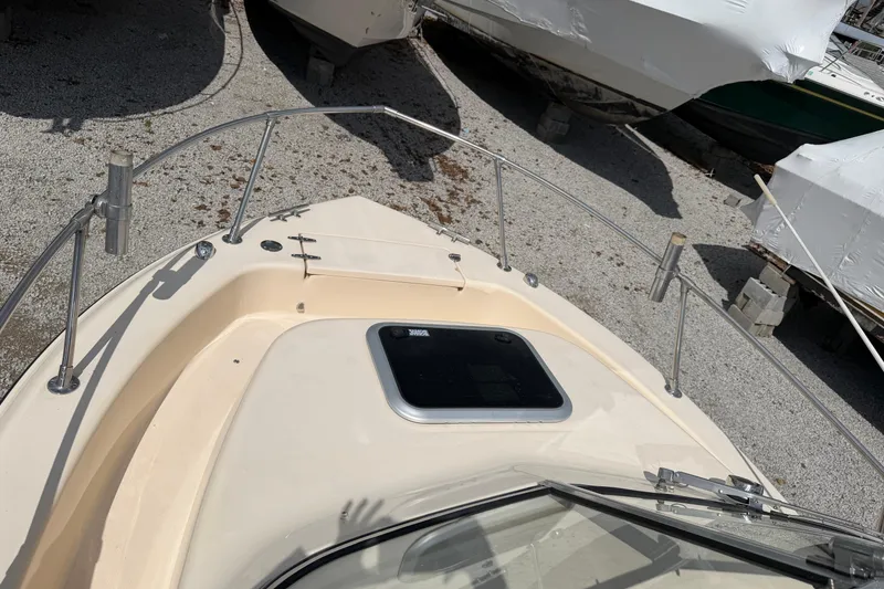 Slide: The Image of 2011 Grady-White Adventure 208 boat deck with railing and hatch, parked on gravel. - 15