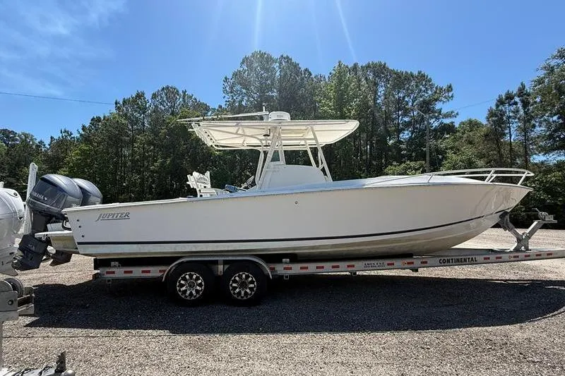 The Image of 2003 Jupiter 31 Cuddy boat on trailer, parked outdoors under clear blue sky. - 1