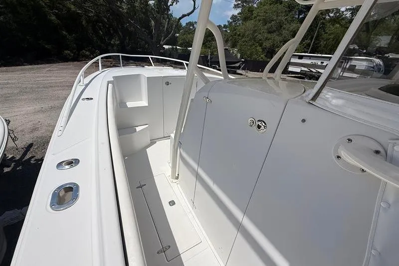 Slide: The Image of 2003 Jupiter 31 Cuddy boat deck with seating and storage, parked outdoors. - 34