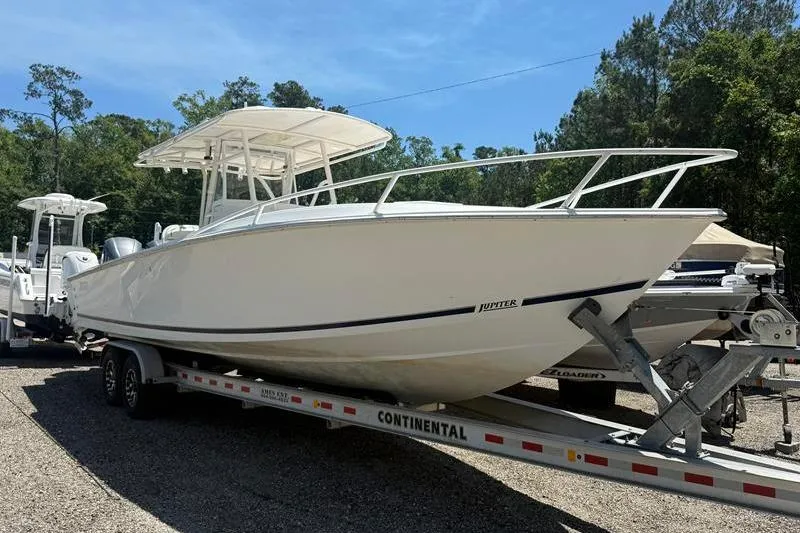 Slide: The Image of 2003 Jupiter 31 Cuddy boat on trailer, parked outdoors, surrounded by trees. - 8