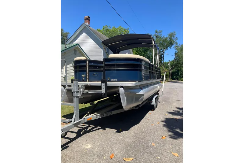 The Image of 2020 Crest Classic DLX 220 SLC pontoon boat on trailer, parked on a sunny street. - 7