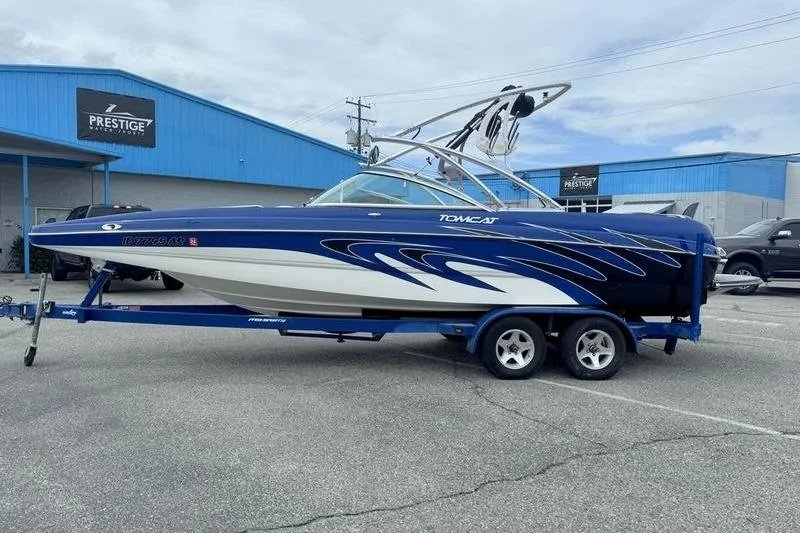 The Image of 2007 MB TOMCAT boat on trailer, blue and white design, parked outside Prestige dealership. - 2