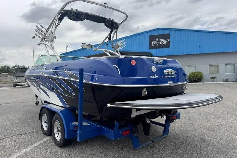 Slide: The Image of Blue 2007 MB TOMCAT boat on trailer, parked outside a blue building under cloudy skies. - 20
