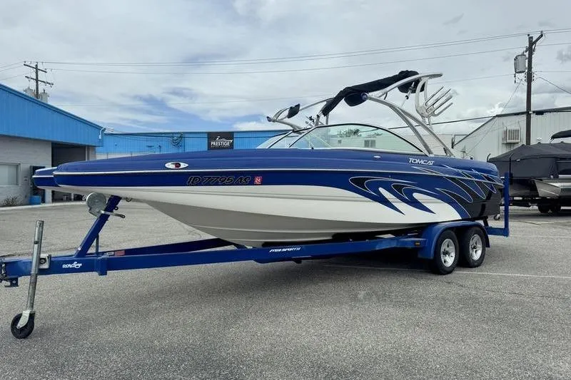 Slide: The Image of 2007 MB TOMCAT boat on trailer, blue and white design, parked outdoors. - 4