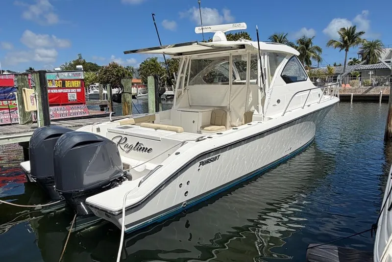 The Image of 2018 Pursuit OS 355 Offshore boat docked, featuring twin outboard engines. - 1