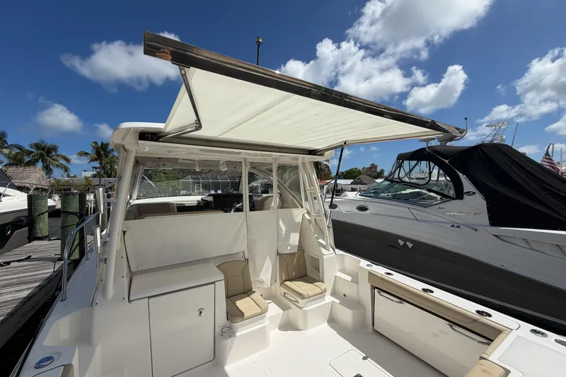 Slide: The Image of 2018 Pursuit OS 355 Offshore boat with canopy, docked under a clear blue sky. - 11
