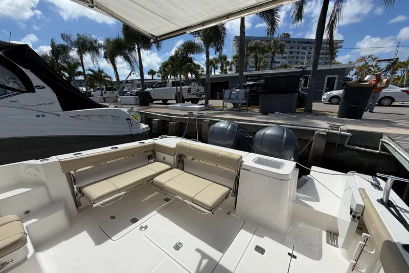 Slide: The Image of 2018 Pursuit OS 355 Offshore boat docked, featuring spacious seating and dual outboard engines. - 12