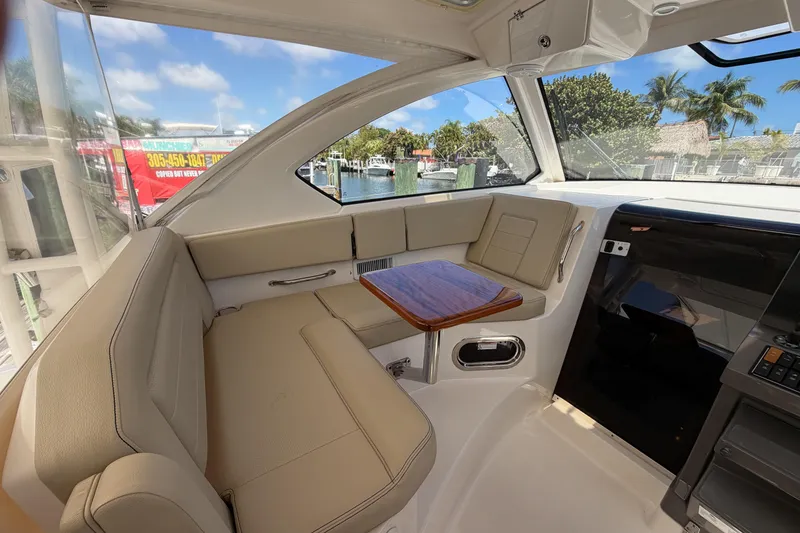 Slide: The Image of Interior of 2018 Pursuit OS 355 Offshore boat with beige seating and wooden table. - 14