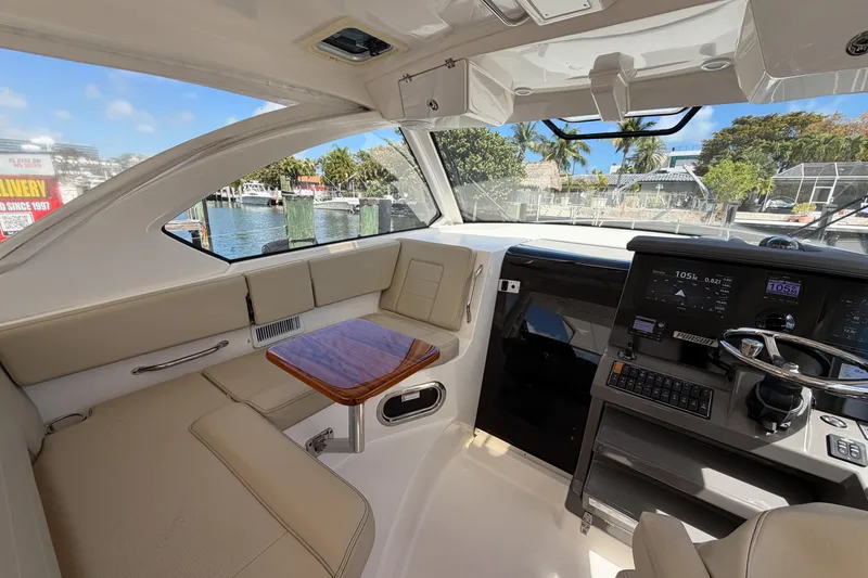 Slide: The Image of 2018 Pursuit OS 355 Offshore boat interior with helm, seating, and waterfront view. - 15