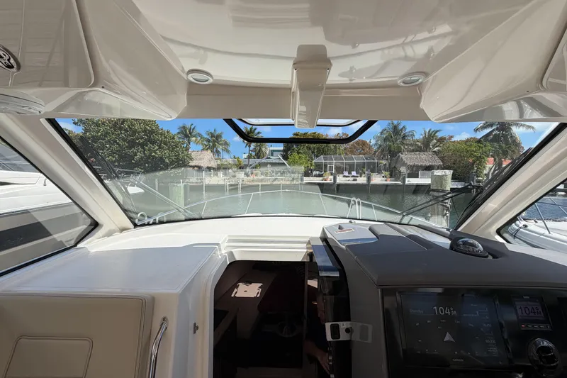 Slide: The Image of Interior view of 2018 Pursuit OS 355 Offshore boat, showcasing helm and waterfront scenery. - 23