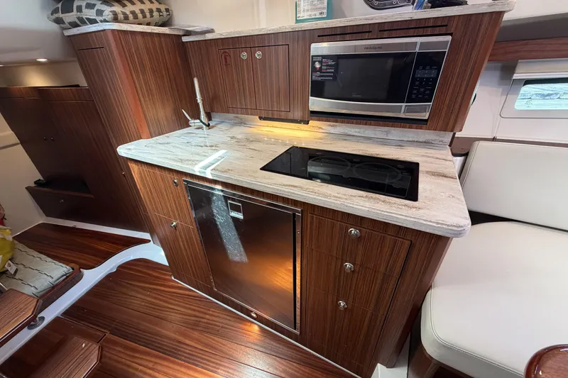Slide: The Image of Luxurious 2018 Pursuit OS 355 Offshore yacht kitchen with wood cabinetry and modern appliances. - 27
