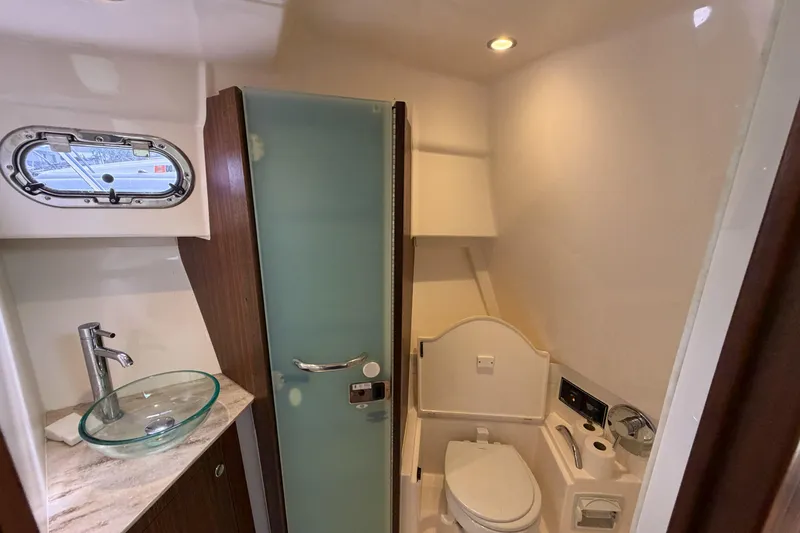 Slide: The Image of 2018 Pursuit OS 355 Offshore bathroom with glass sink, toilet, and frosted glass door. - 29