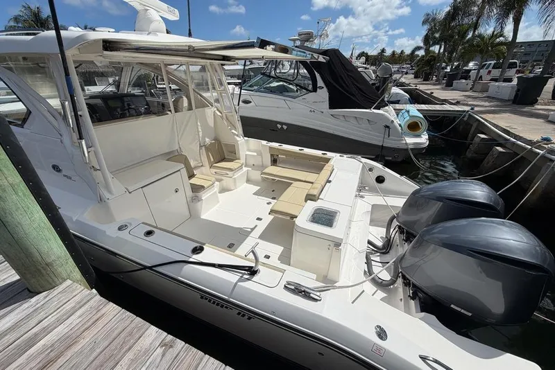 Slide: The Image of 2018 Pursuit OS 355 Offshore boat docked, featuring dual outboard engines and spacious seating. - 3