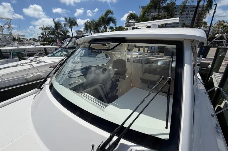 Slide: The Image of 2018 Pursuit OS 355 Offshore boat docked, showcasing sleek design and spacious interior. - 33