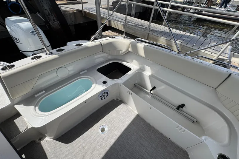 Slide: The Image of 2022 Stingray 192 SC boat interior with seating, storage, and cup holders at a dock. - 18