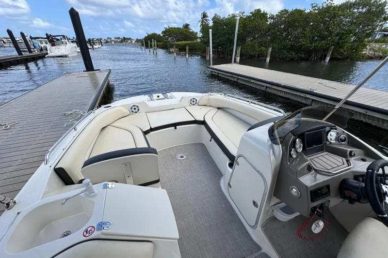 Slide: The Image of 2022 Stingray 192 SC boat interior with seating and helm, docked by a marina. - 22