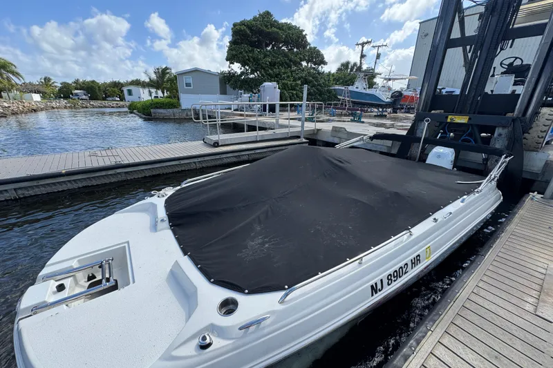 Slide: The Image of 2022 Stingray 192 SC boat docked with cover, surrounded by marina scenery. - 39