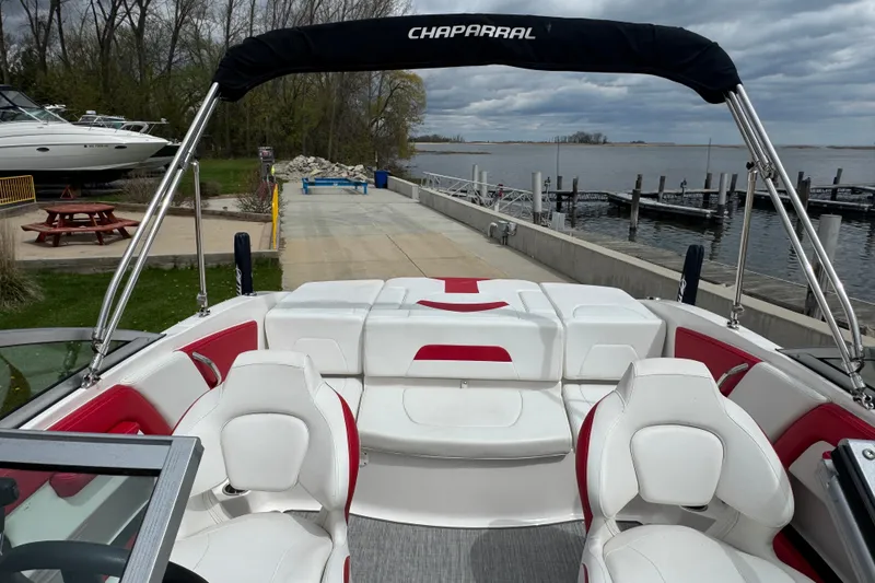 Slide: The Image of 2017 Chaparral 21 H2O Sport boat with white and red seating, docked by a lake. - 32