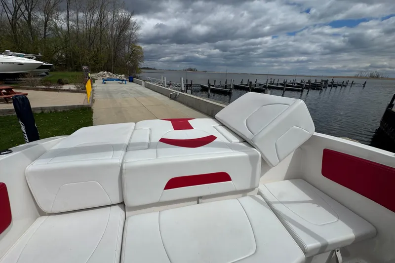 Slide: The Image of 2017 Chaparral 21 H2O Sport boat with white and red seating, docked by a serene lake. - 7
